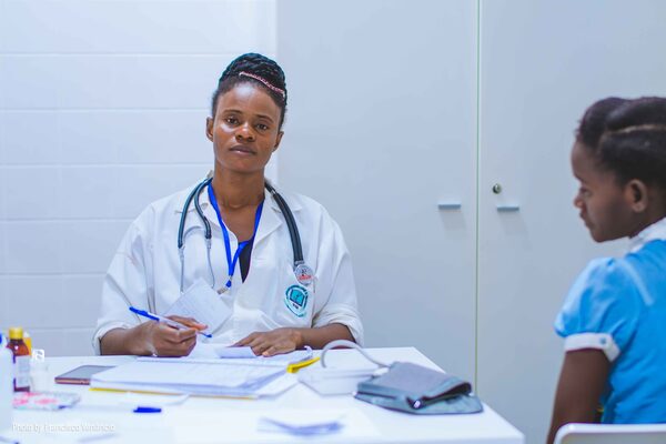A clinician at a desk with a young girl in a clinic