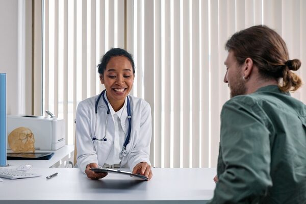 A physician at a desk talking with a patient